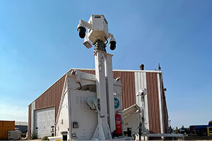 A mobile surveillance trailer with solar security cameras offers parking lot and commercial video security outside an industrial building.