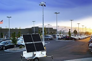 A solar-powered mobile surveillance trailer provides parking lot security with commercial mobile video and solar security camera systems at sunset.