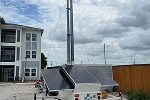 Mobile surveillance trailer with solar security camera provides parking lot security near homes.