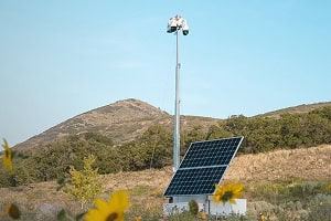 A mobile surveillance trailer with solar security camera and commercial video system in a grassy field.