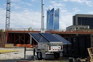 A solar-powered mobile surveillance trailer with security cameras at a commercial construction site for parking lot and video security.